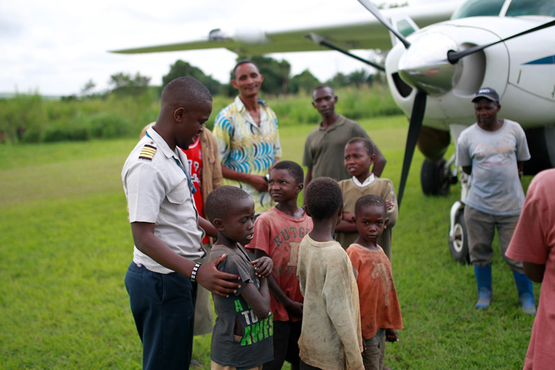 Group of men and children gathered by plane
