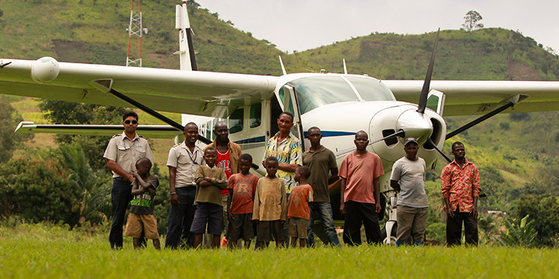 Group of children and men in front of plane mountains in background